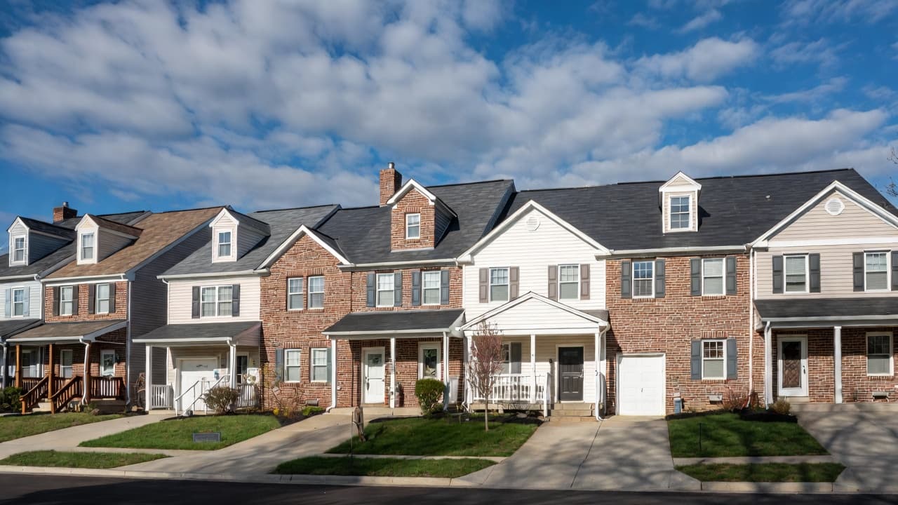 A row of brick and siding townhomes on a neighborhood street