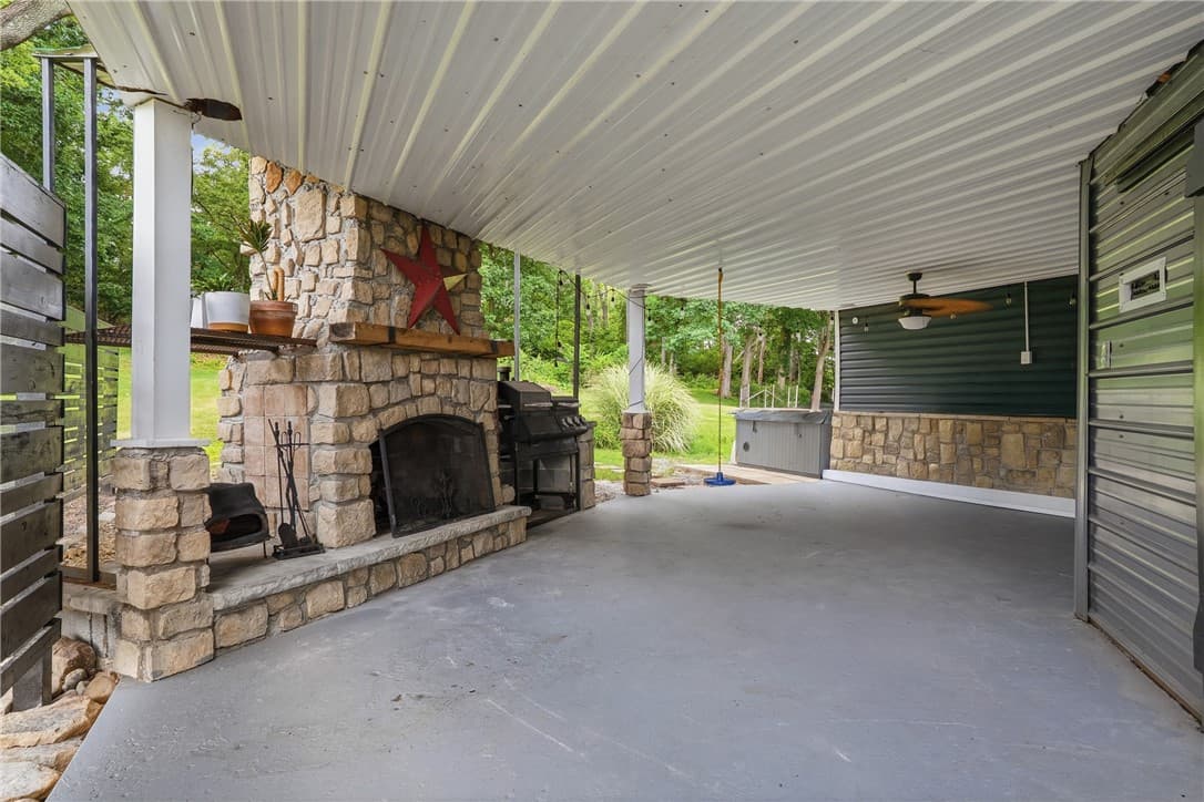Covered patio with a stone wood-burning fireplace